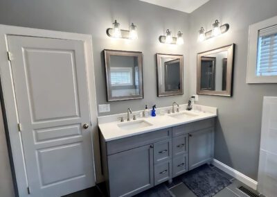 Modern bathroom remodel featuring a double vanity with gray cabinets, quartz countertop, dual mirrors, and contemporary lighting — completed by Central Connecticut Building & Remodeling in Berlin, CT.