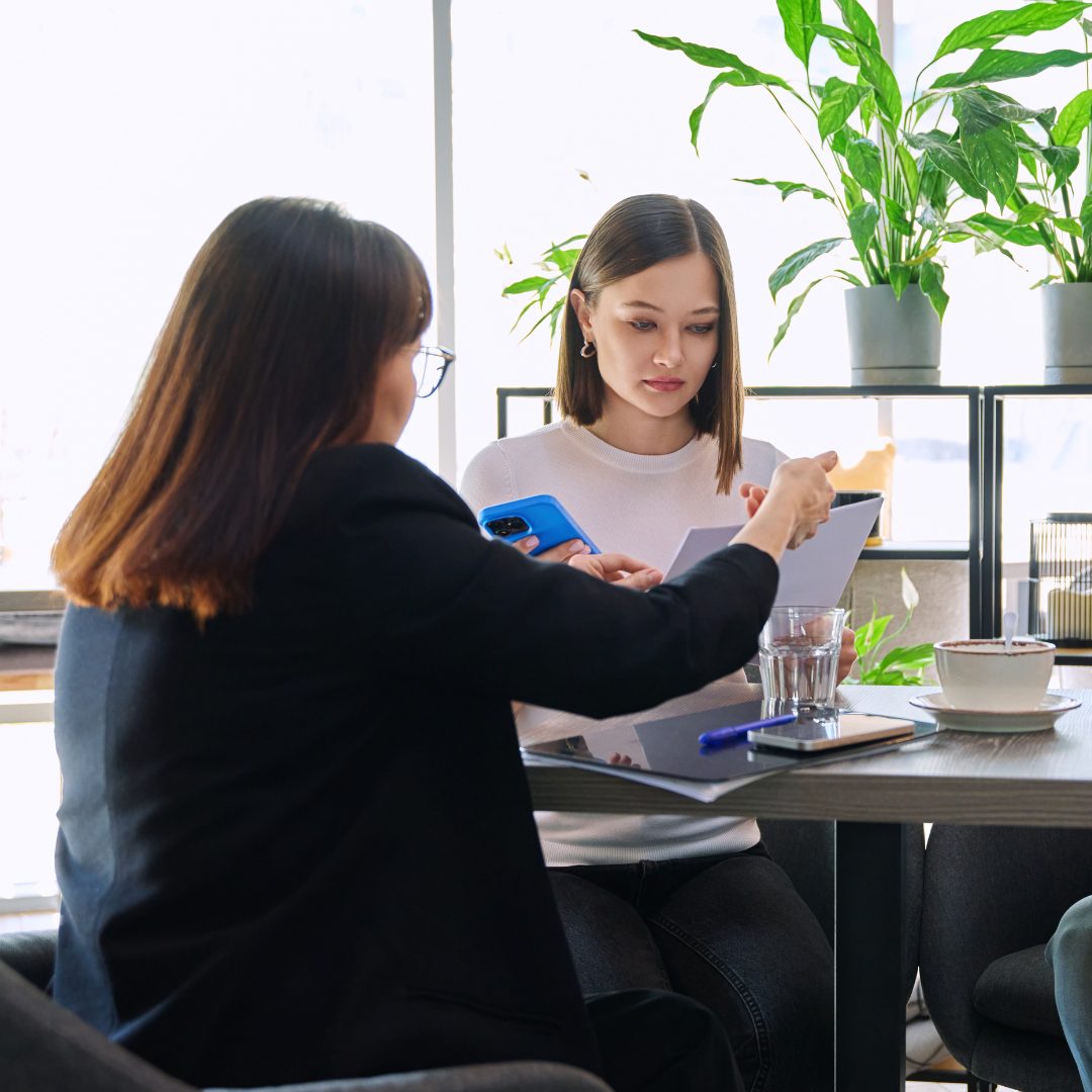 Homeowner meeting with an insurance adjuster at a table, reviewing storm damage paperwork and discussing claim details.